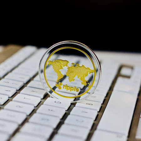 Digital currency physical metal ripple coin on the white computer keyboard.の写真素材
