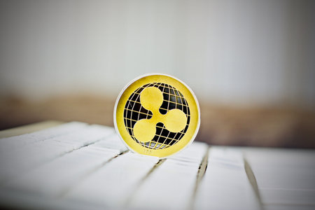Digital currency physical metal ripple coin on the white computer keyboard.