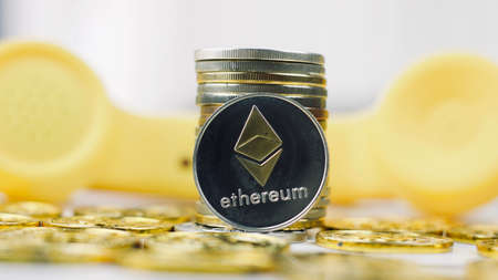 Digitl currency physical metal ethereum coin. Cryptocurrency yellow phone concept.の写真素材