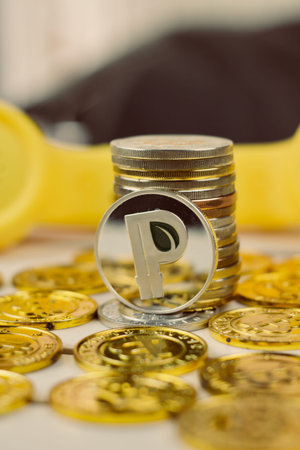 Digital currency physical metal silver coin near yellow phone.