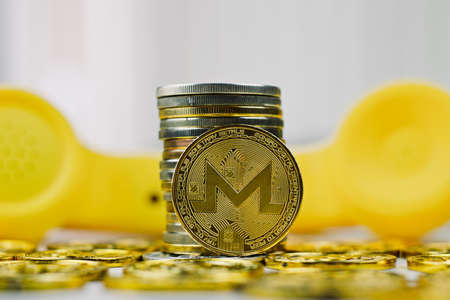 Digital currency physical metal monero coin. Yellow phone concept.の写真素材
