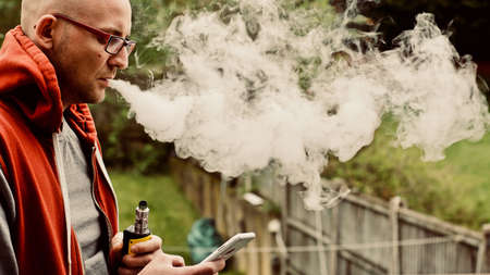 Young man vaping outdoor. E-cigarette concept.の写真素材