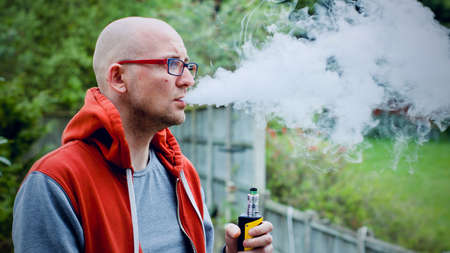 Young man vaping outdoor. E-cigarette concept.の写真素材