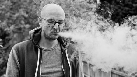 Young man vaping outdoor. E-cigarette concept.