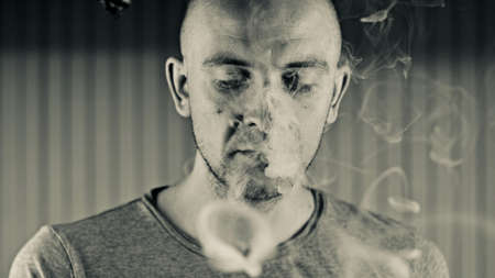 Young bald man smoking e-cigarette to quit tobacco. Vapor and alternative nicotine free smoking concept.の写真素材