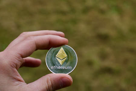 Digital currency physical metal silver ethereum coin. Cryptocurrency outdoor concept.の写真素材