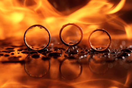 beautiful wedding rings on fire with reflection and in waterの写真素材