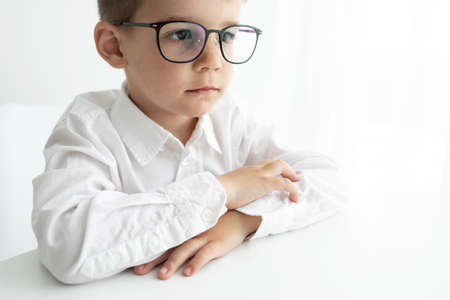 Cute little boy using laptop while doing homework against white backgroundの写真素材