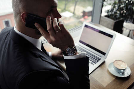Close up of handsome businessman, working on silver laptop in restaurantの写真素材