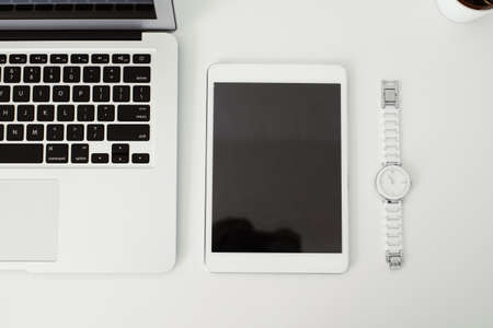 office table on which laptop, coffee, tablet, camera and other itemsの写真素材