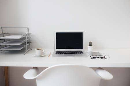 office table on which laptop, coffee, tablet, camera and other itemsの写真素材