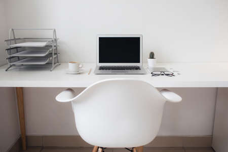 office table on which laptop, coffee, tablet, camera and other itemsの写真素材