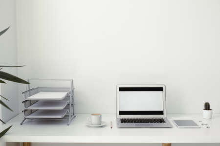 office table on which laptop, coffee, tablet, camera and other itemsの写真素材