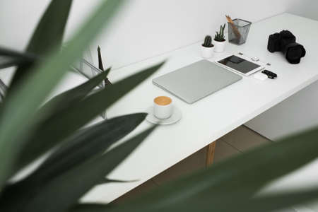 office table on which laptop, coffee, tablet, camera and other itemsの写真素材