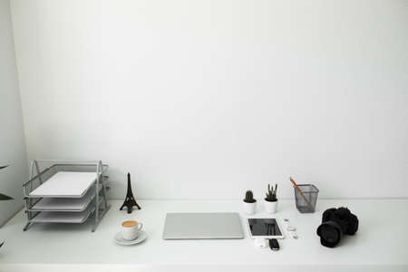 office table on which laptop, coffee, tablet, camera and other itemsの写真素材
