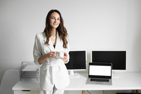 the girl drinks a cup of coffee in a bright office