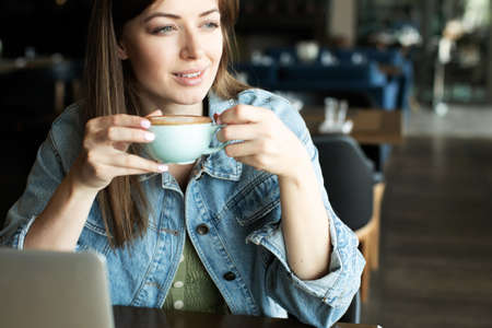 young girl smiling and drinking delicious coffeeの写真素材