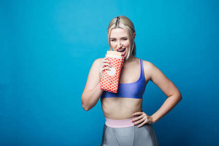 Close up of hungry girl with opened mouth, holding and eating big hamburger. Pretty woman with beautiful hairstyle and red lips. Concept of fast food.の写真素材