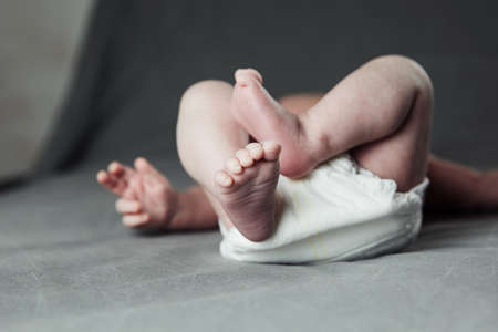 Newborn baby belly and legs in diaper, lying on white bed, top view, copy space. Newbornの写真素材