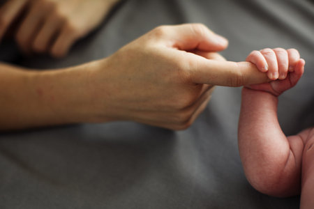 Mother holding newborn baby hands in hands. Mom taking care about infant child after taking bath....