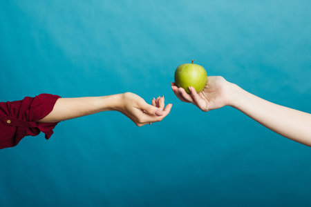 The hand passes the apple to the other hand. Health