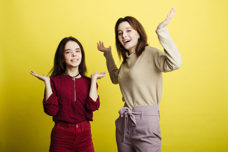 Image of happy young girls standing isolated over yellow background. Girls