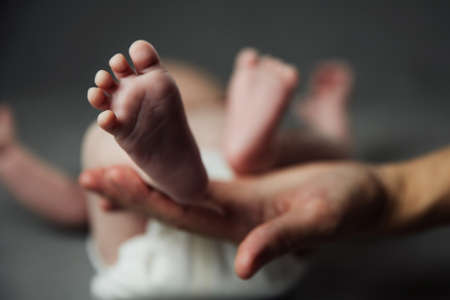 Mother holding newborn baby feet in hands. Mom taking care about infant child after taking bath. Parents childcare. Children healthcare and happy familyの写真素材