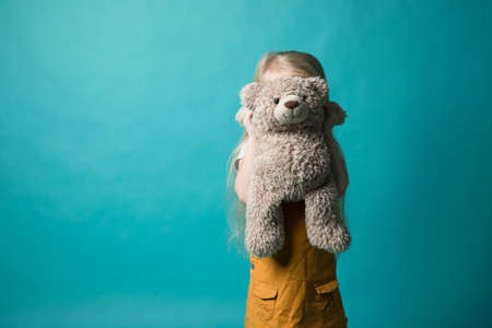 Girl on a blue background hugging a gray bearの写真素材