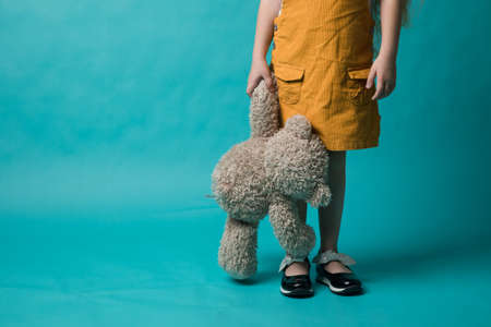girl on a blue background, holding in hands a grey bear. Toysの写真素材