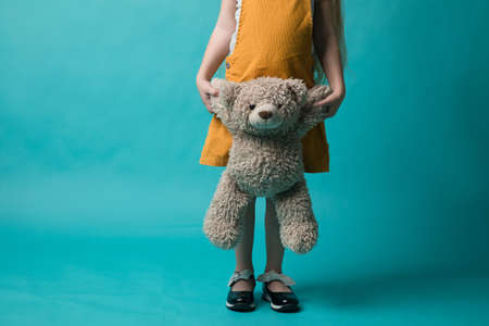 girl on a blue background, holding in hands a grey bear. Toysの写真素材
