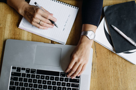 Portrait of a young woman in glasses. Young business woman working with laptop and writing notes in...