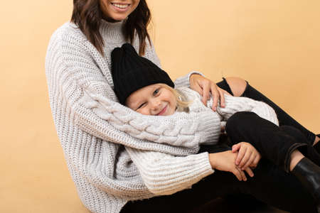 A young and energetic mother hugs and kisses her son on an orange backgroundの写真素材