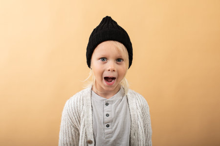 little boy in sweater and hat on yellow background. winter