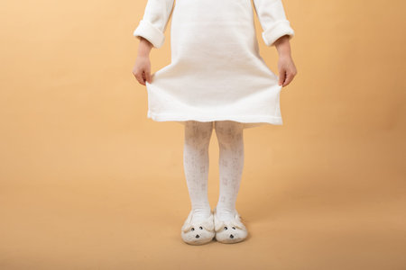 A little girl in a white knitted dress and a black hat. Very nice and cheerful girl