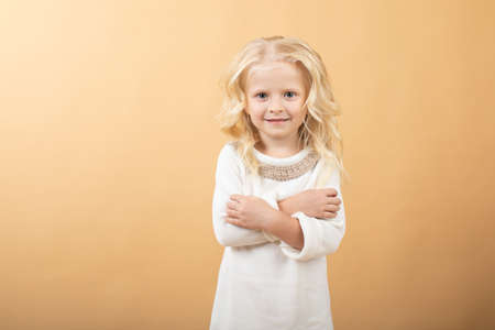 A little girl in a white knitted dress. Very nice and cheerful girlの写真素材