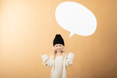 A girl in a hat stands on an orange background and shows emotions