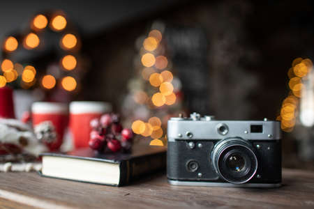 Retro camera is on the table on the background of Christmas songs and Christmas treesの写真素材