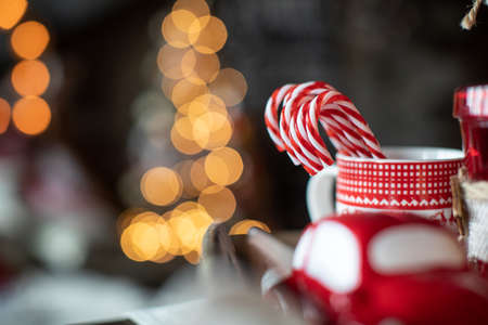 Red Christmas mugs with sweets are on the table on the background of the Christmas treeの写真素材