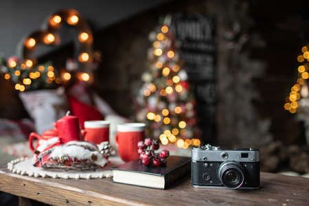 Retro camera is on the table on the background of Christmas songs and Christmas treesの写真素材