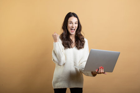 An image of a young beautiful woman in a white sweater posing on an isolated orange background with...