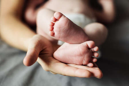 Mother holding newborn baby feet in handsの写真素材