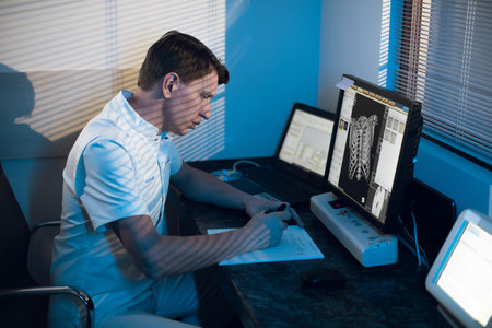 in medical laboratory patient undergoes MRI or CT scan process under Supervision of Radiologist in Control Room, He Watches Procedure and Monitors skeleton and ribs of the patientの写真素材