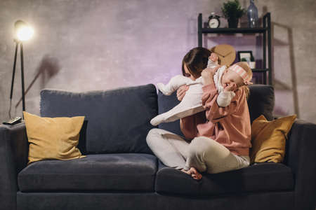 A woman plays with her child on the couch in a cozy apartment. Mom and baby are happy.の写真素材