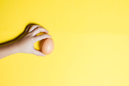 Fresh egg in hands on a yellow background