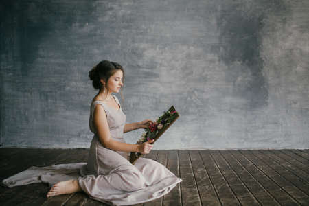 Girl in a Pink Dress Looks at Fresh Flowers on a Board on a Gray Backgroundの写真素材
