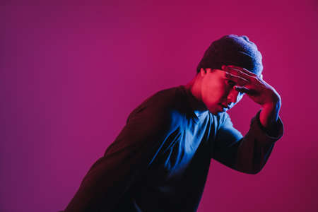 Young Man in a Jumper Dancing Contemporary Dance in Studio. Breakdancing. Dance School Poster. Copy Space. Battle competition announcement. Pink and Blue Background.の写真素材