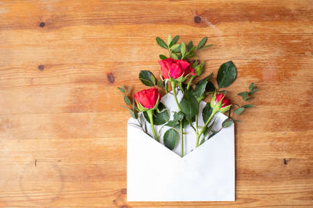 Beautiful flowers on a wooden table with an envelope. The work of the florist. Flower delivery.の写真素材