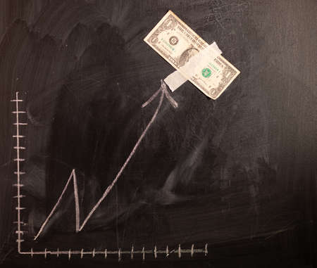 Dollar growth chart drawn on chalkboard. Investment concepts and interests Business growth. Rising graph made out of dollars.の写真素材