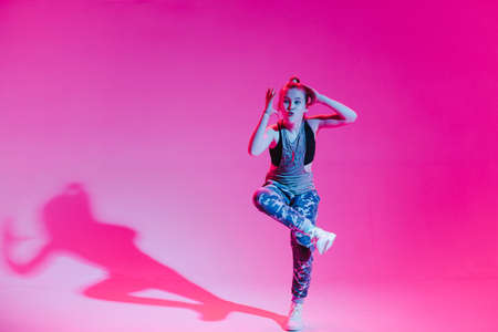 Young stylish girl dancing in the Studio on a colored neon background. Music dj poster design.の写真素材
