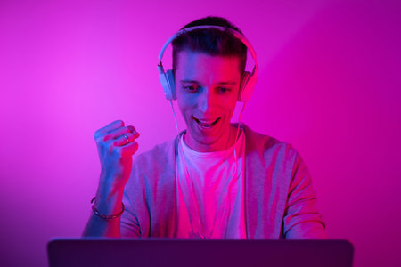 Gamer plays on a laptop. The programmer writes the code. Man on a colored background
